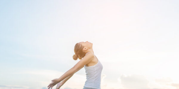 Young beautiful woman raising hands with beautiful view at meadow enjoy fresh air.
